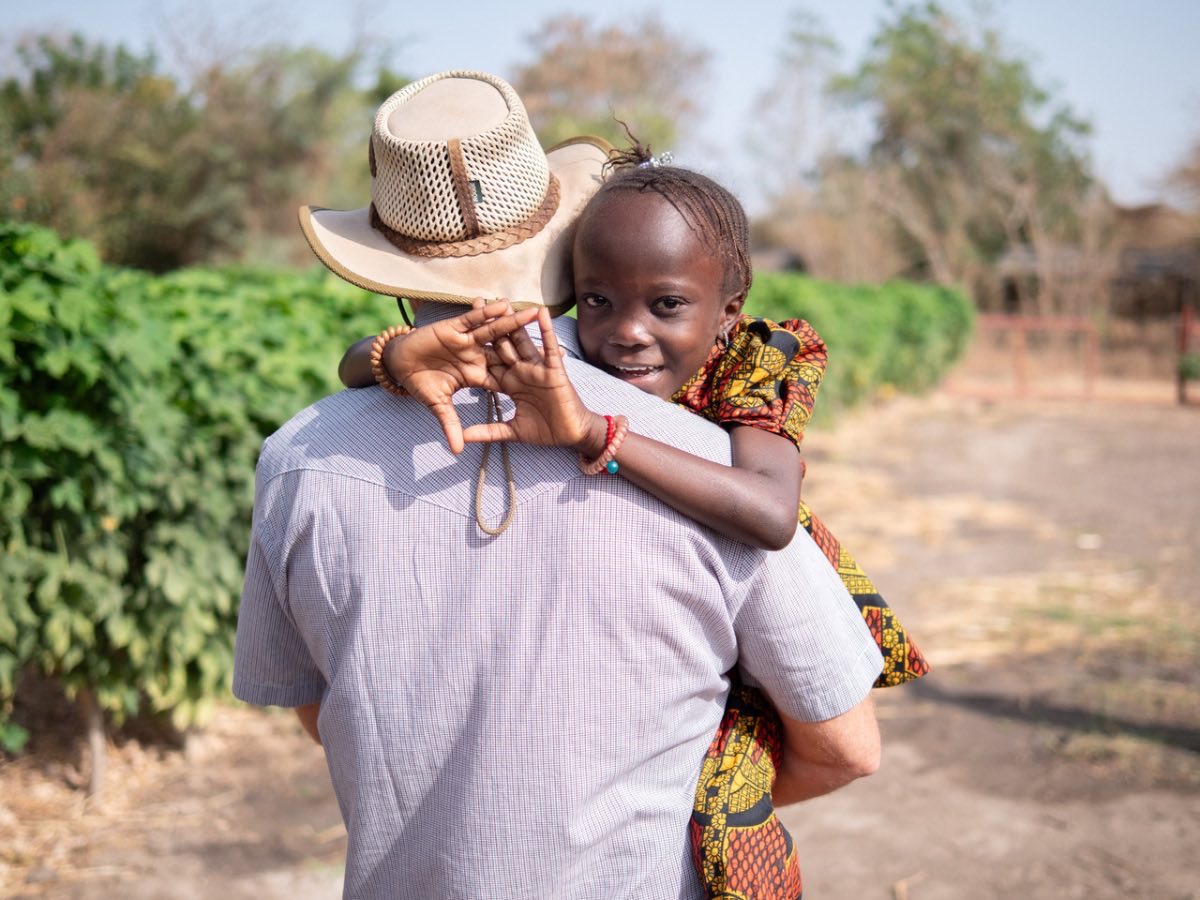 A girl smiling over the shoulder of the worker carrying her at the farm