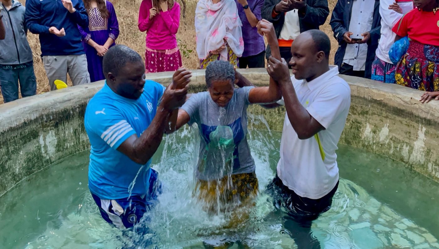 A woman being baptized while the congregation looks on