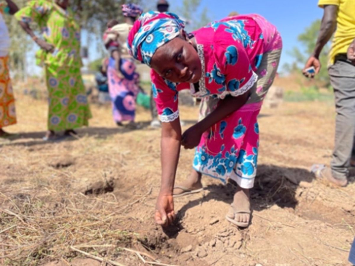 A woman planting seed by hand in a prepared field