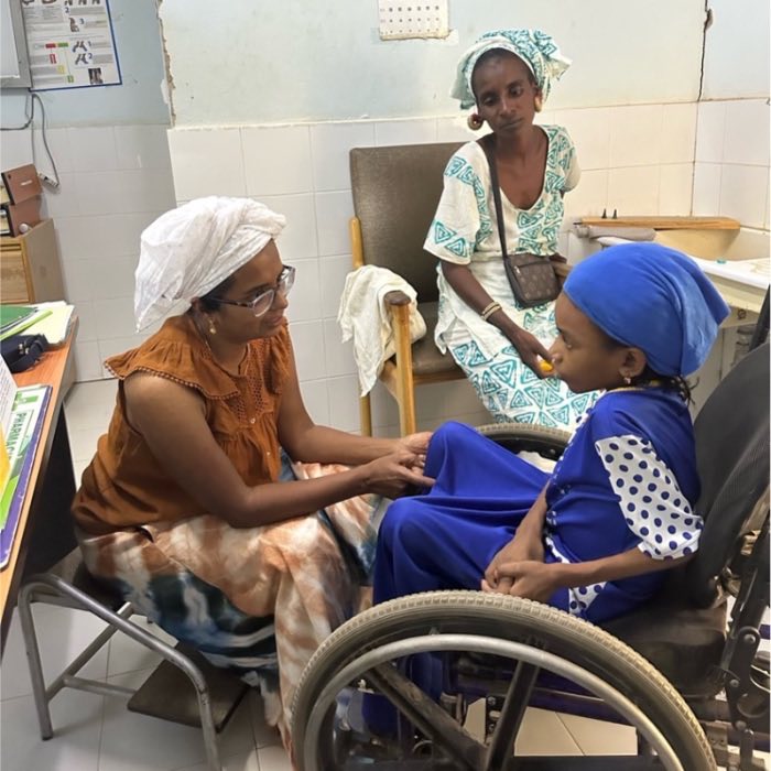 Suja Brane talking with a patient in a wheelchair at the clinic