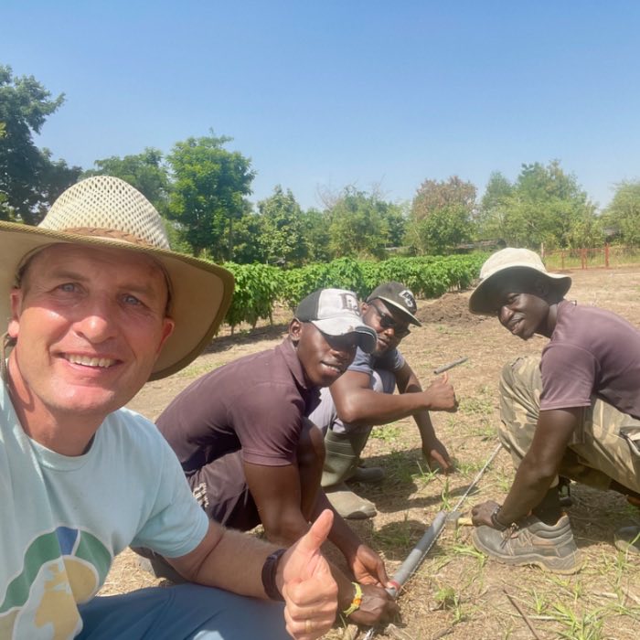 Tom Brane and farmers kneeling together in a field